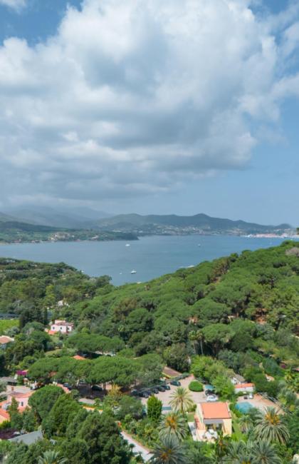 Panoramablick auf Meer und grüne Hügel unter bewölktem Himmel.