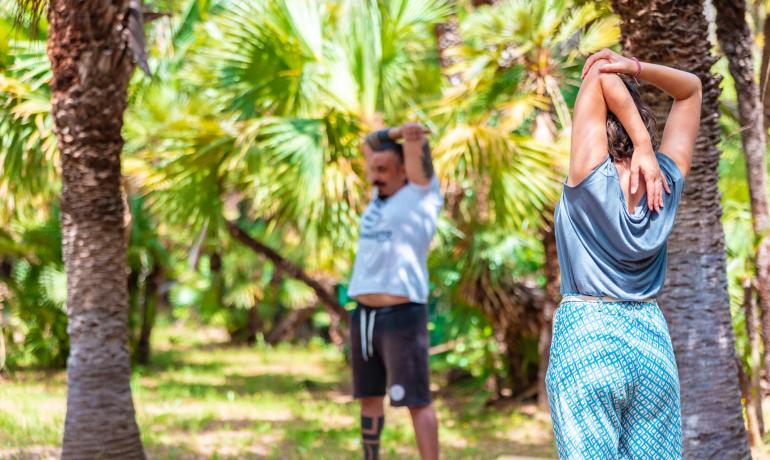 Two people stretching in a tropical garden.