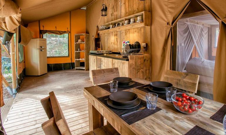 A glamping tent with kitchen, dining table, and bedroom.