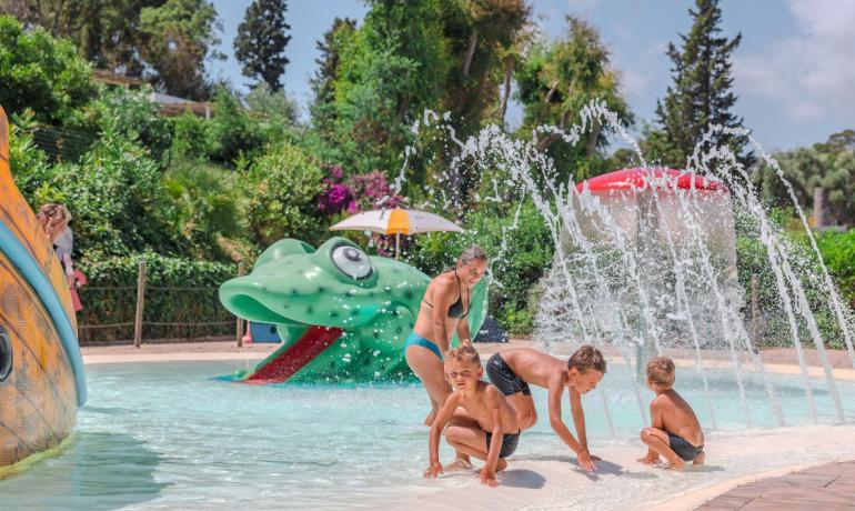 Bambini giocano in piscina con sculture d'acqua.