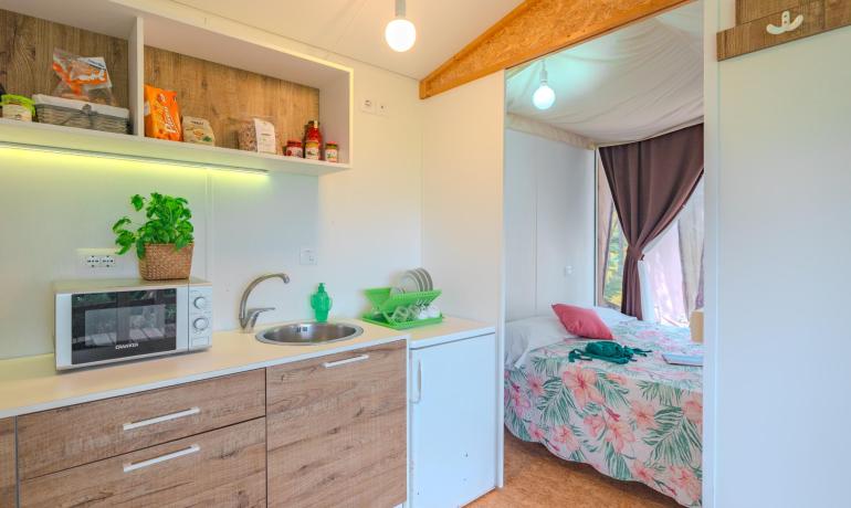 Cucina compatta con camera da letto accogliente, decorazioni floreali e colori vivaci.